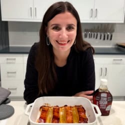 Maya leaning over a baking dish of maple glazed salmon.