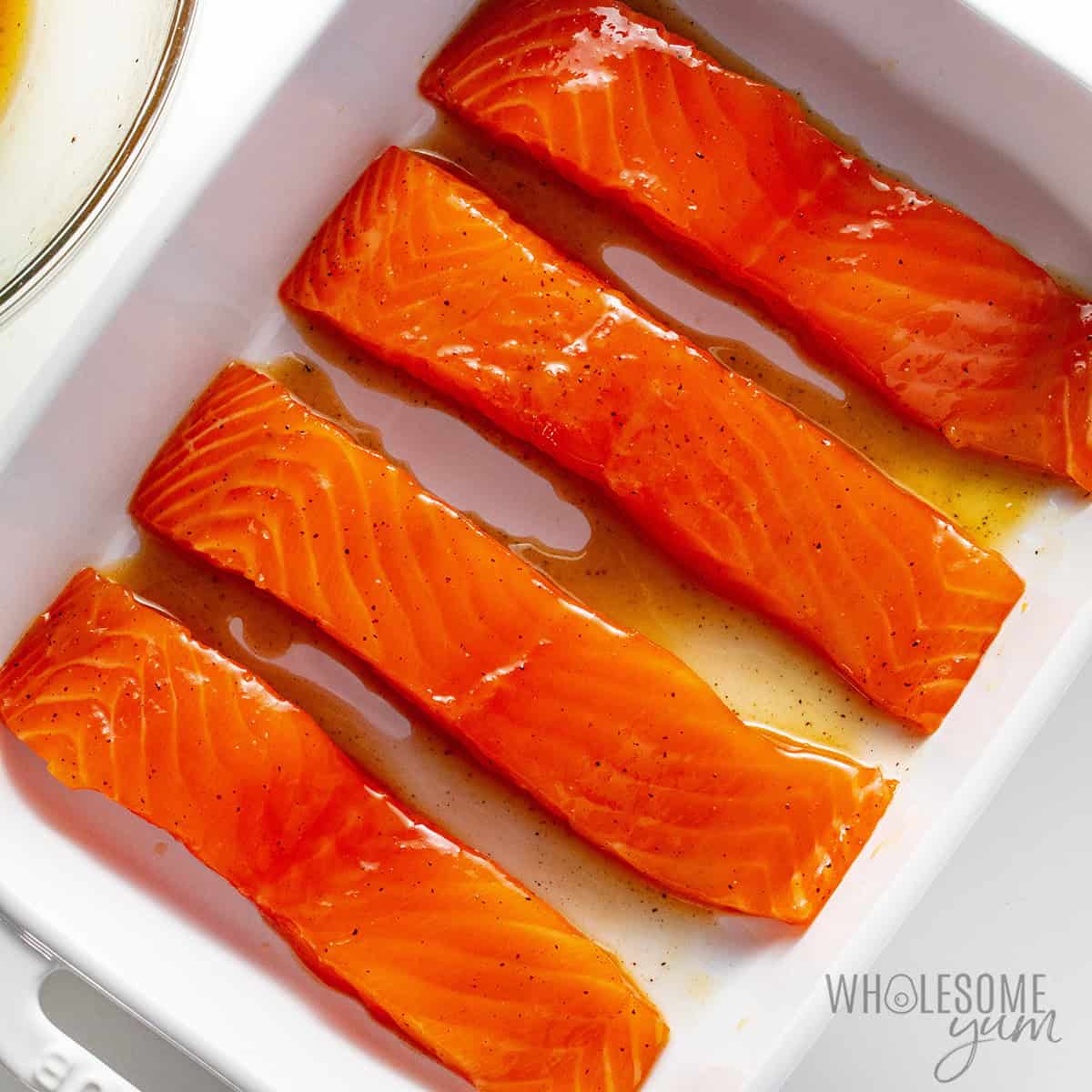 Salmon arranged in a baking dish with space between the pieces.