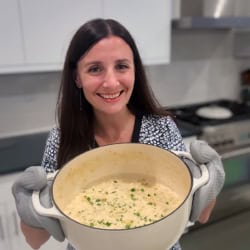Maya holding a large pot of creamy clam chowder.