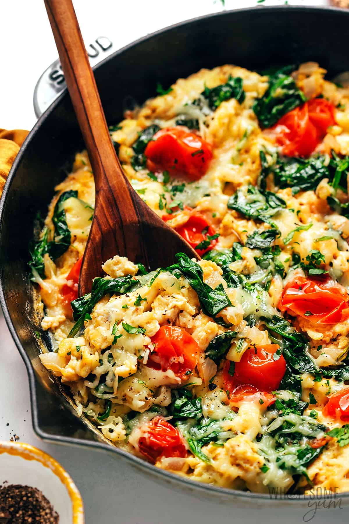 Fluffy breakfast egg scramble with veggies scooped with a spoon.