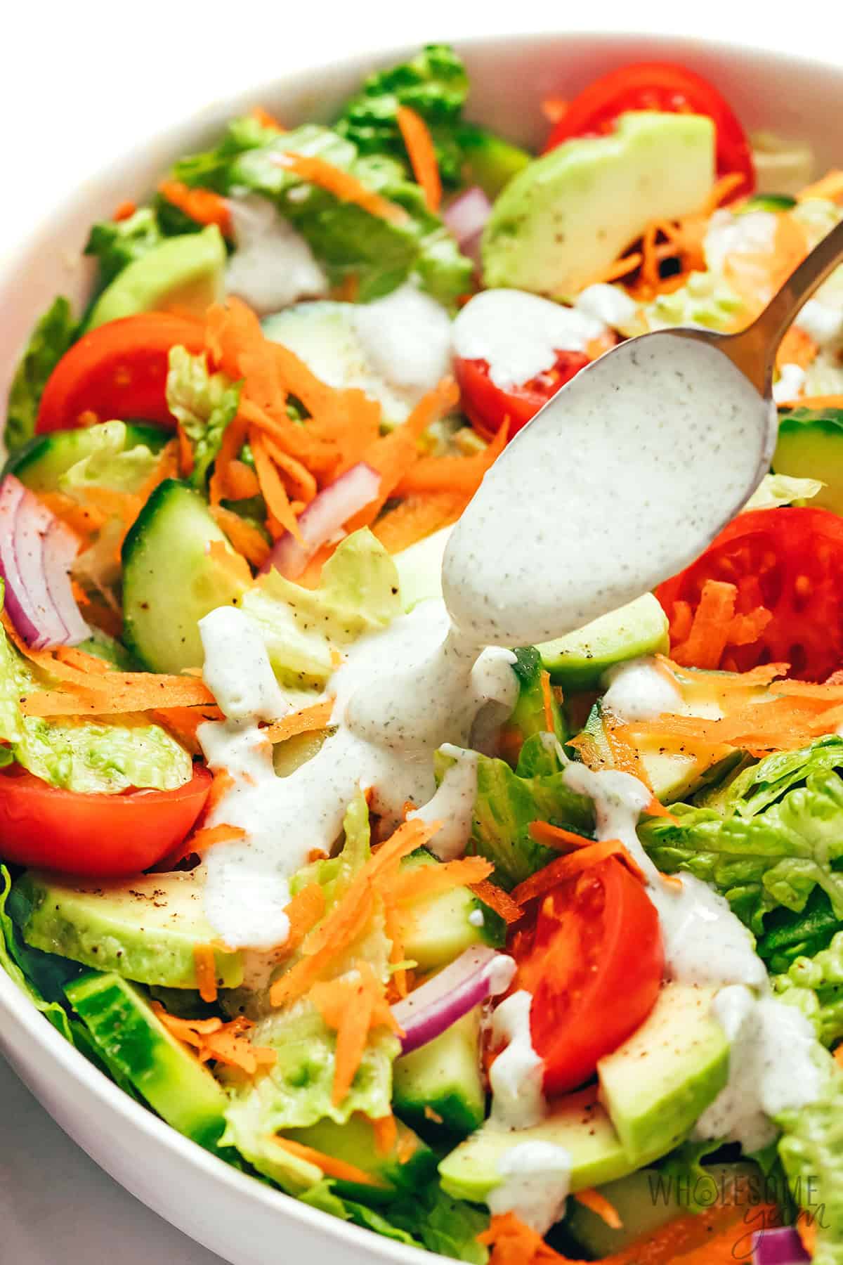 Drizzling Greek yogurt ranch on a salad.