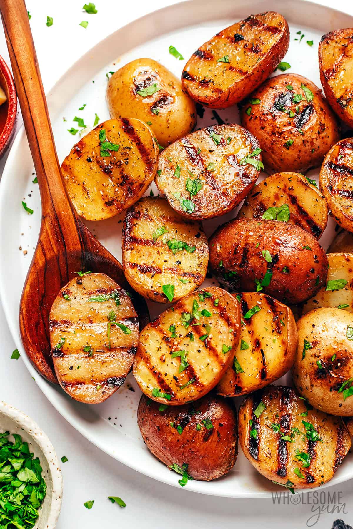 Fluffy grilled potatoes with grill marks on a plate with a serving spoon.