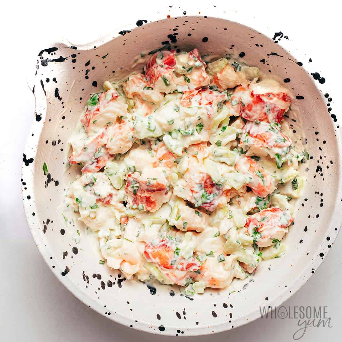 Mixing lobster pieces into the creamy base for a Maine style lobster roll.