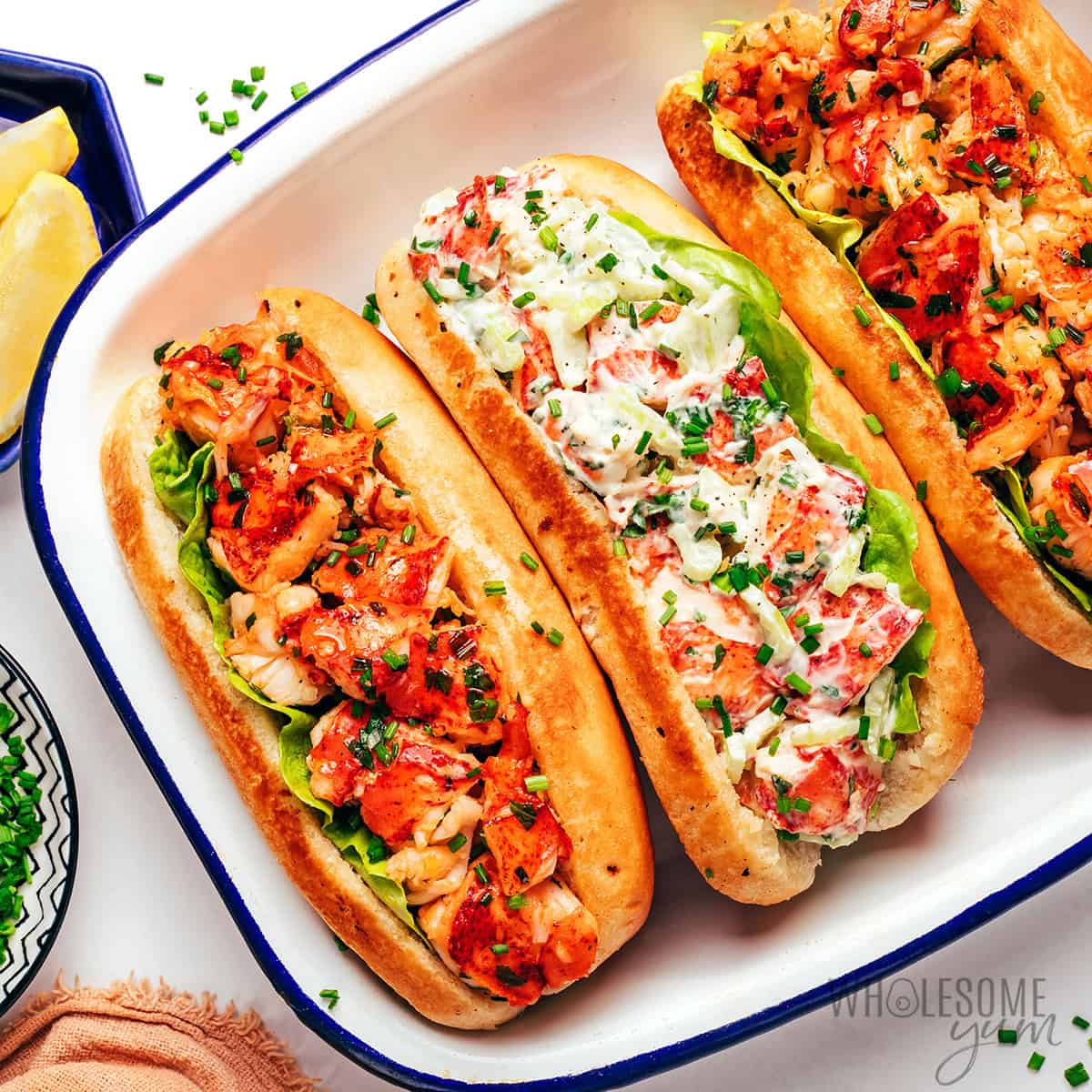 Lobster rolls on a plate, including both Connecticut buttery style and Maine creamy style.