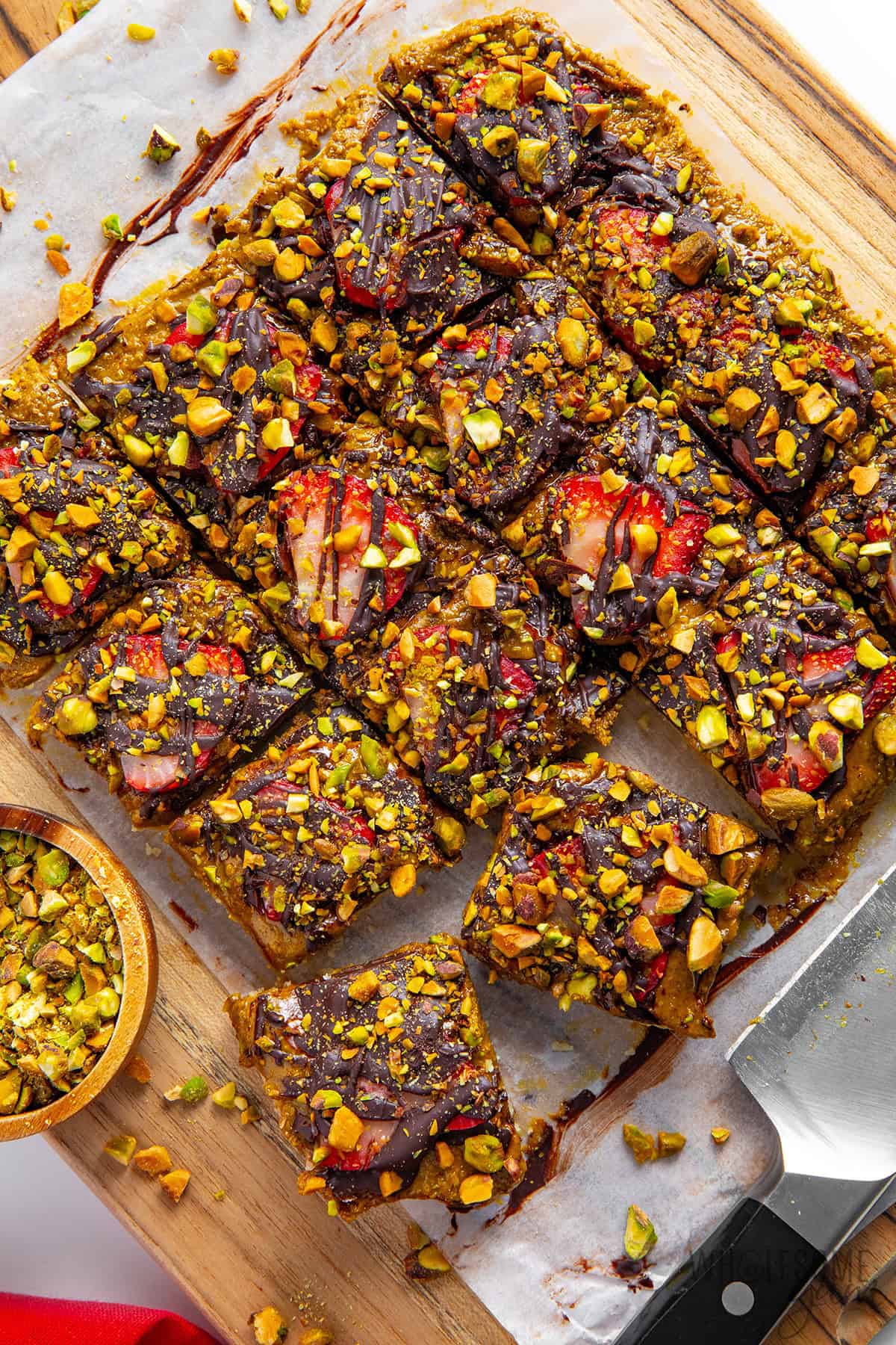 Pistachio chocolate bars cut into squares on a cutting board.