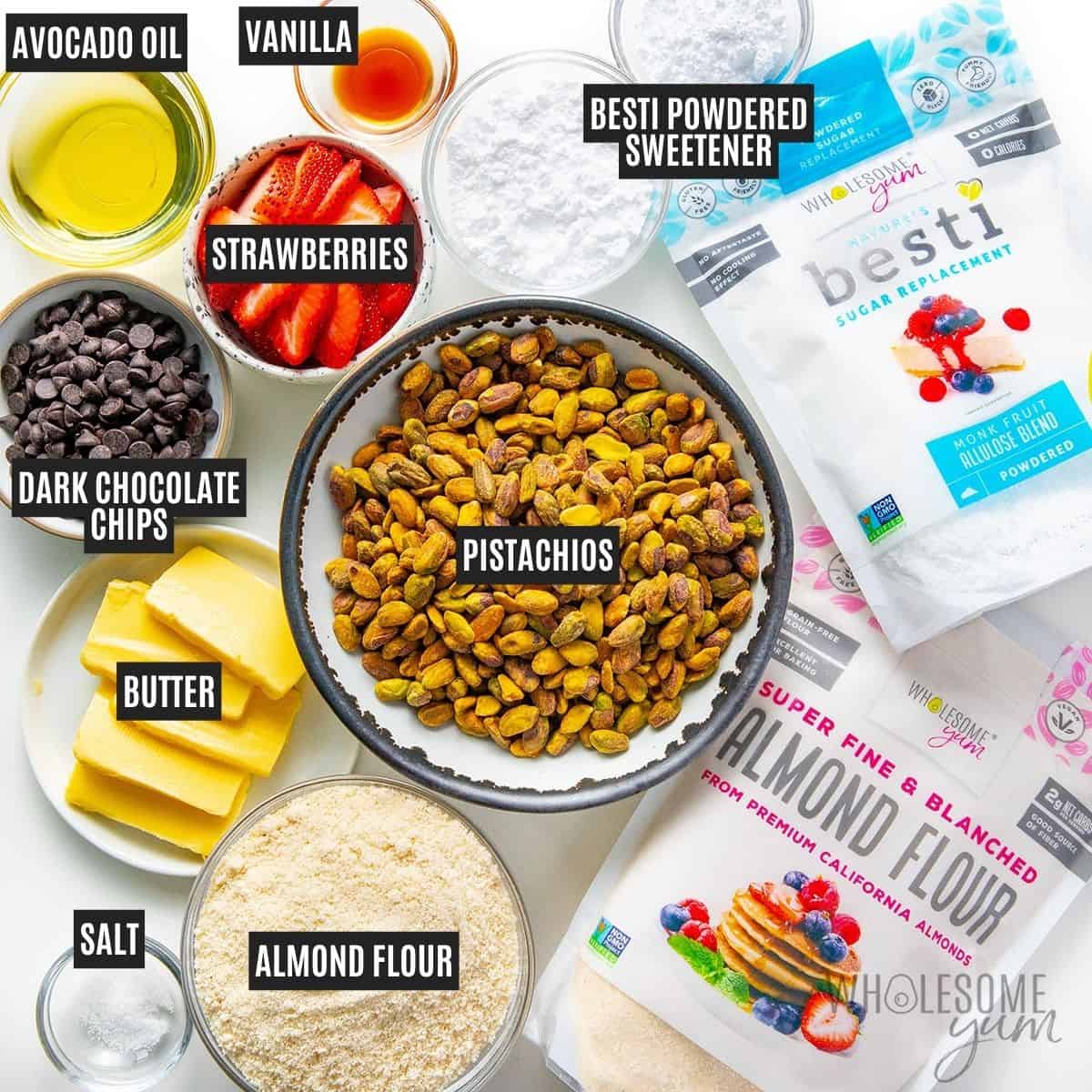 Labeled recipe ingredients: Pistachios, Wholesome Yum Blanched Almond Flour, Besti Powdered Monk Fruit Allulose Blend, unsalted butter, avocado oil, vanilla extract, powdered sweetener, strawberries, chocolate chips, and sea salt.