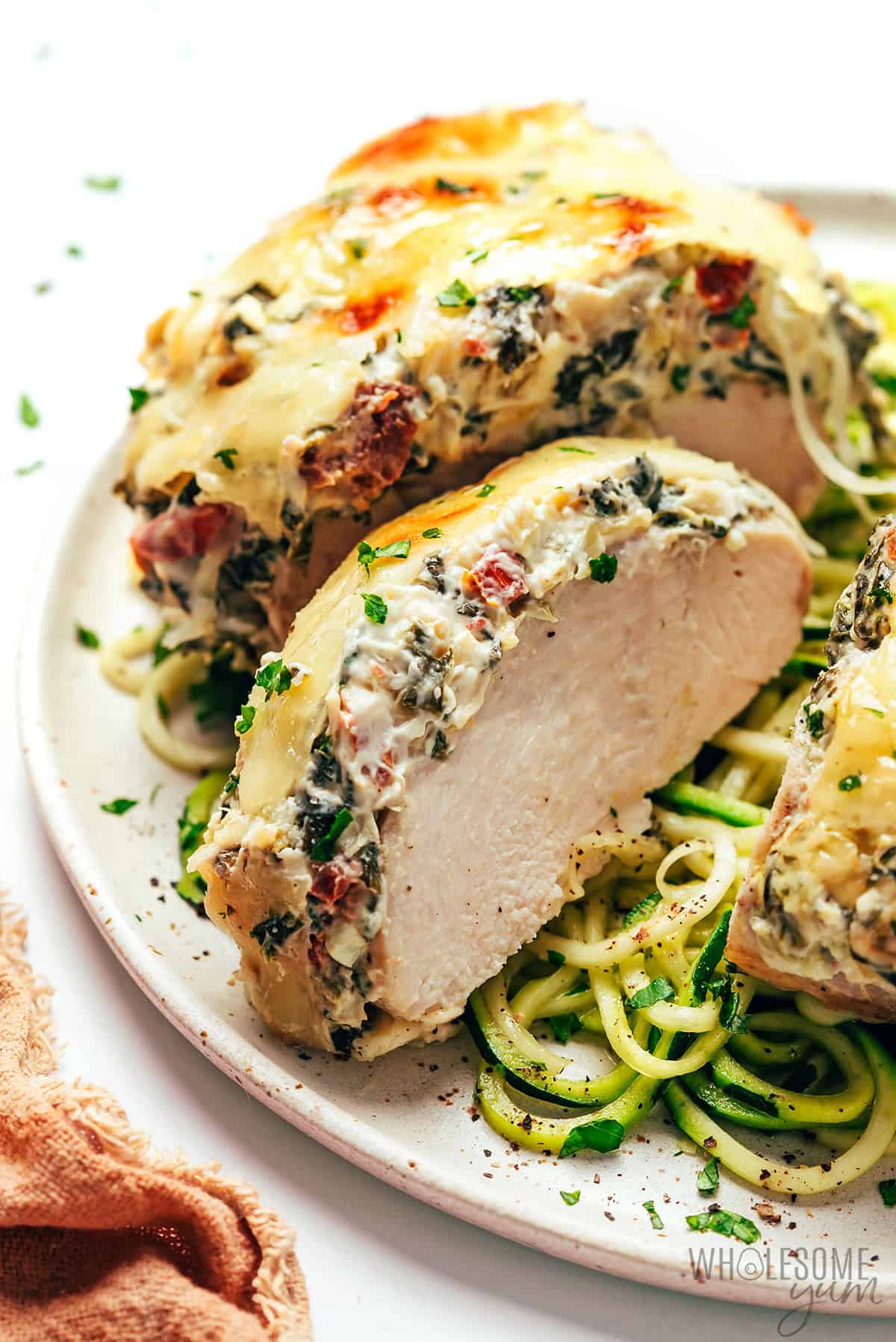 Cheesy, tender spinach artichoke chicken sliced to show the creamy, melty topping.