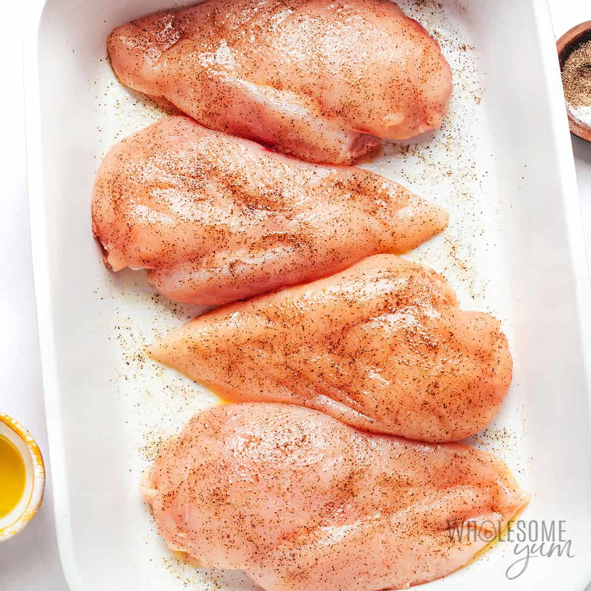 Seasoned chicken breasts in a baking dish.
