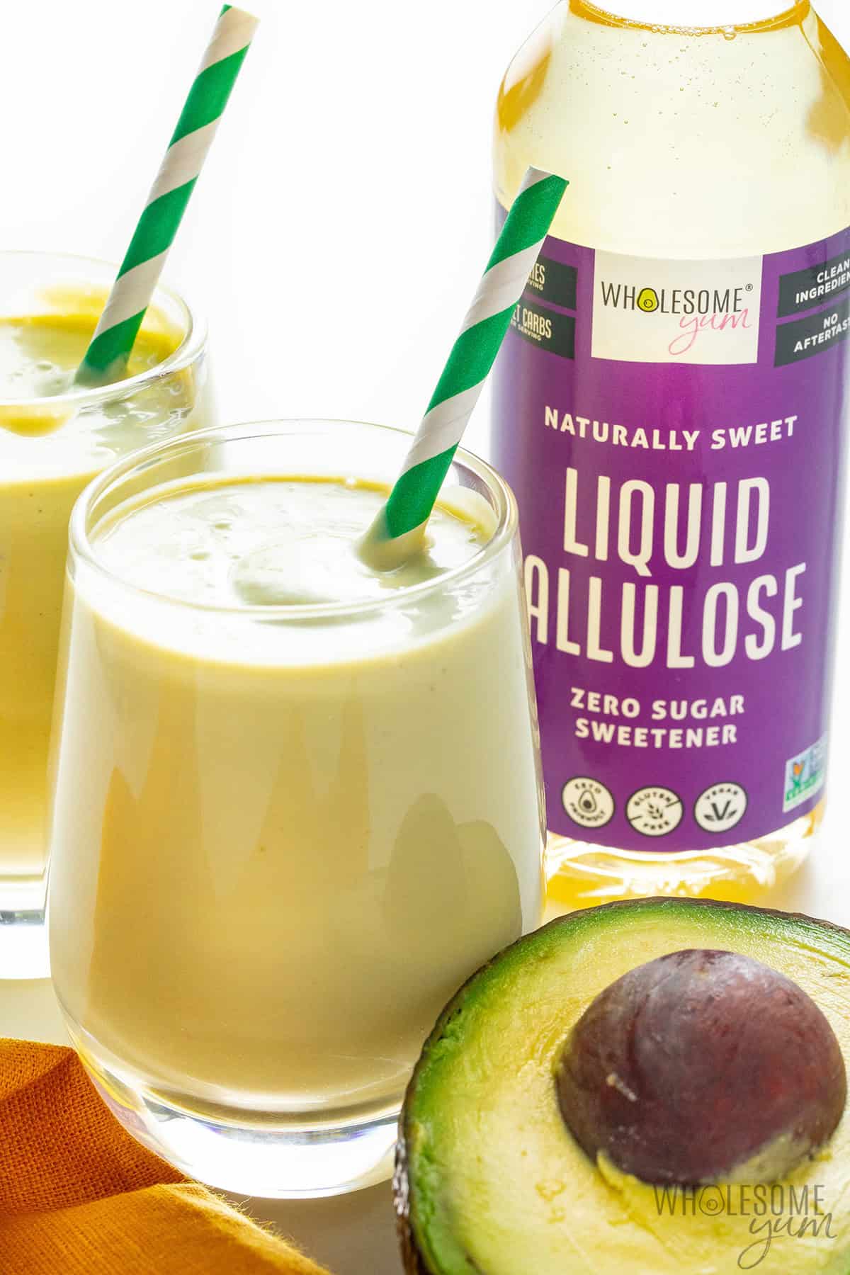 Thick, creamy avocado smoothie in glasses with straws.
