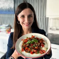 Maya holding a serving bowl with creamy bruschetta dip.
