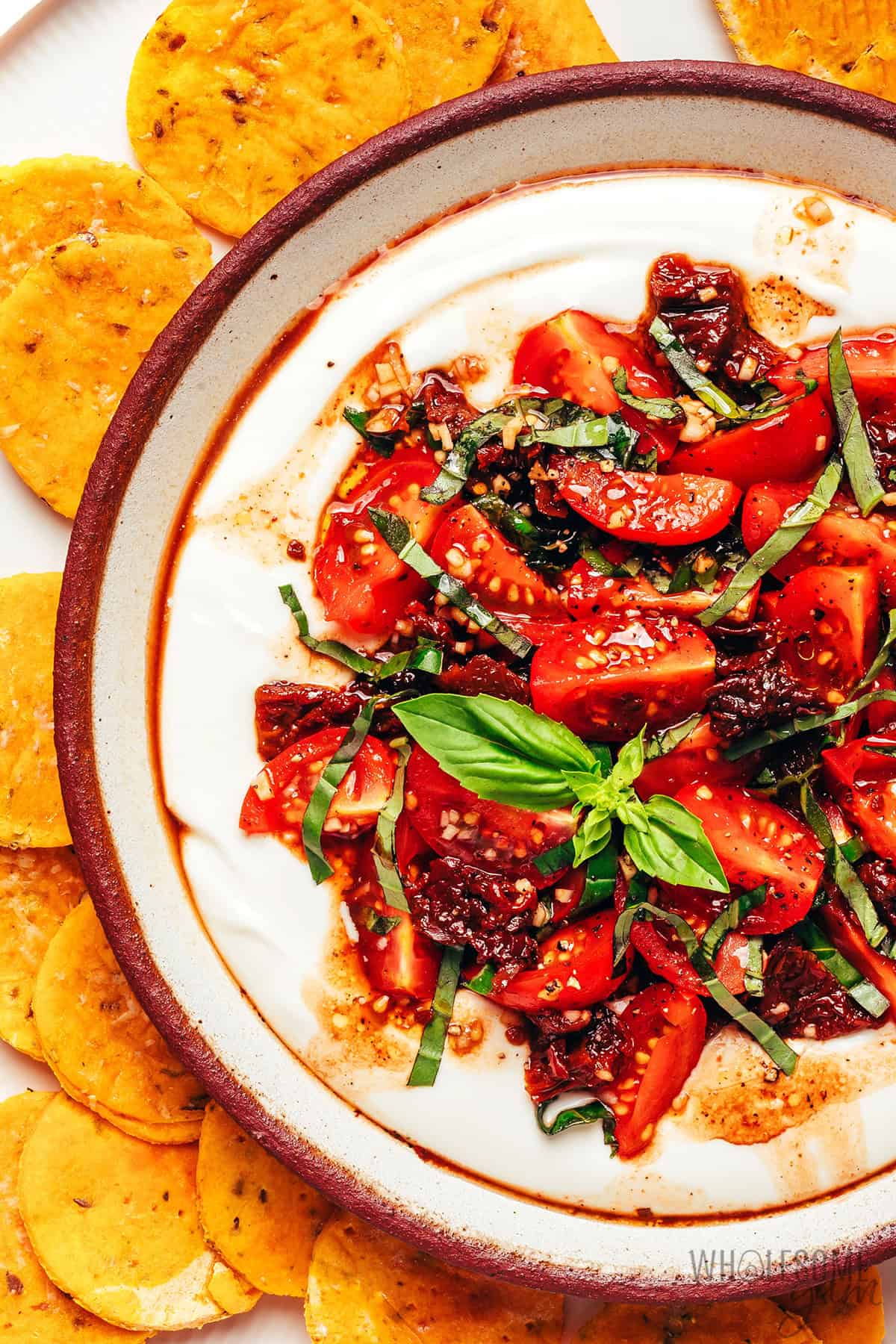 Bruschetta dip with fresh tomatoes, sun-dried tomatoes, balsamic, and fresh basil over a creamy base.