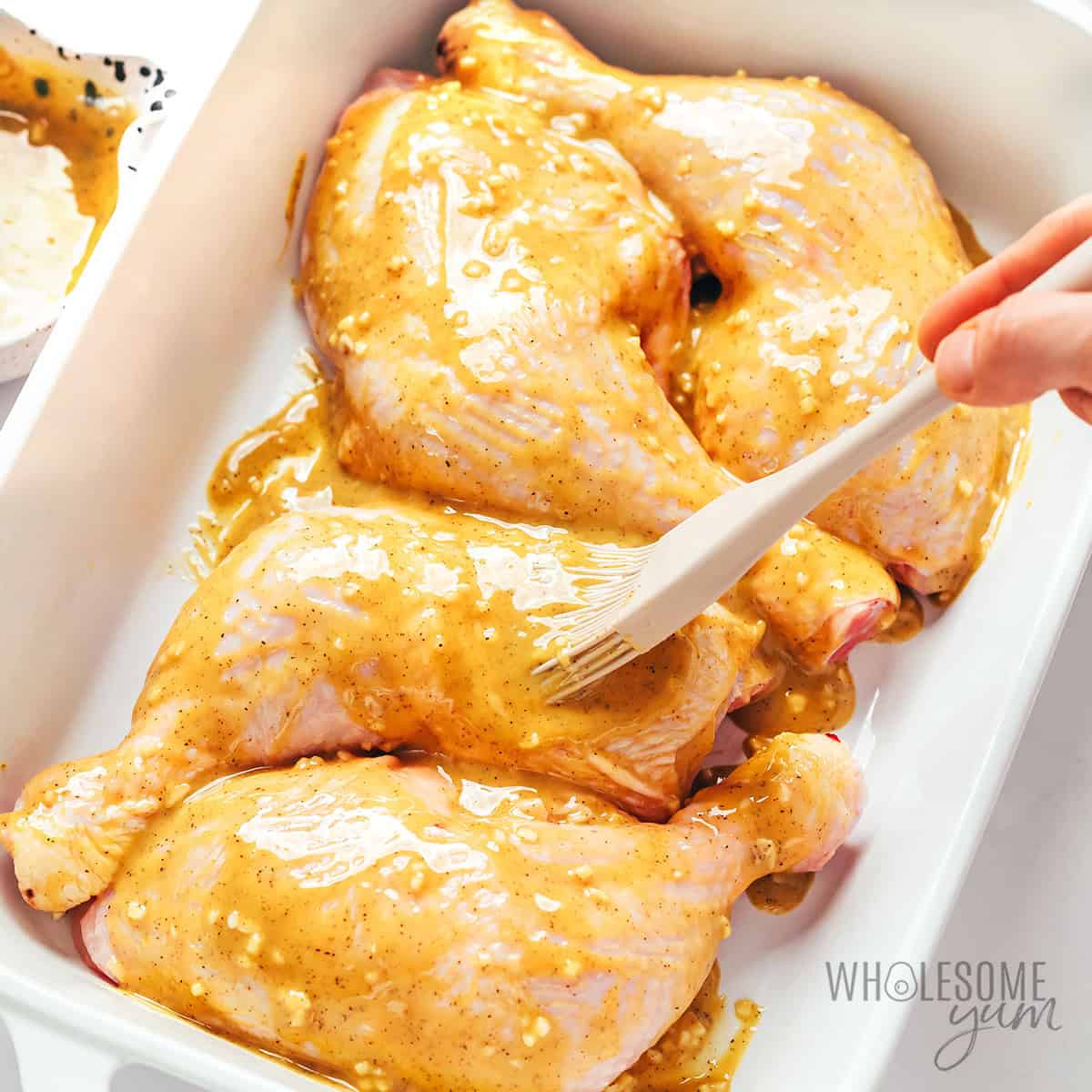 Brushing the marinade over the chicken quarters.