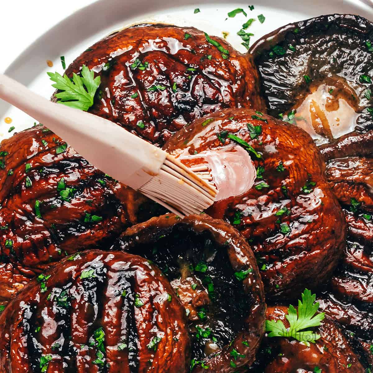 Finished grilled portobello mushroom recipe on a plate, brushed with remaining marinade.