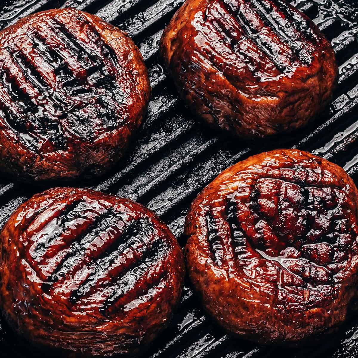 Grilling portobello mushrooms, with grill marks on the caps.