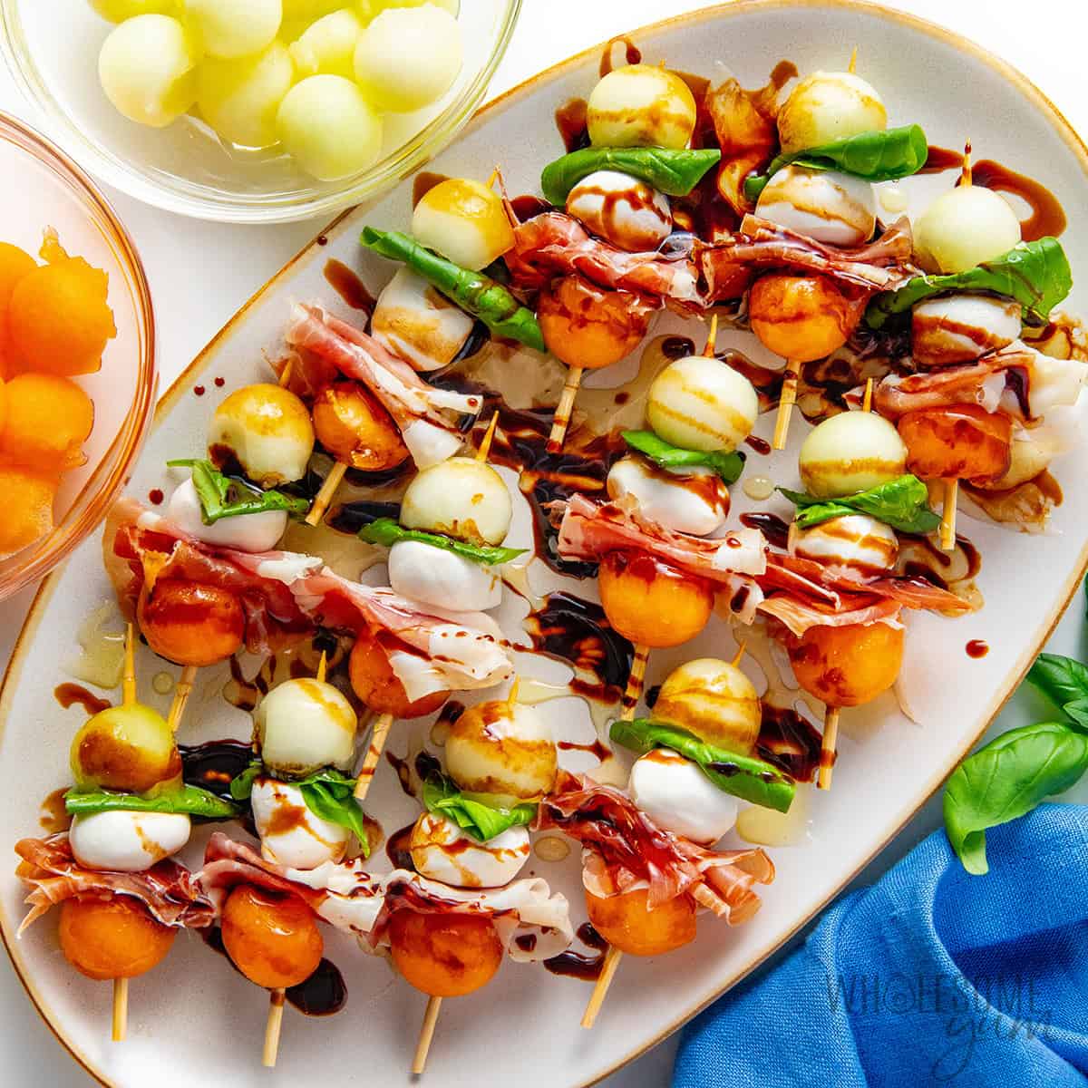 Prosciutto and melon skewers on a platter.