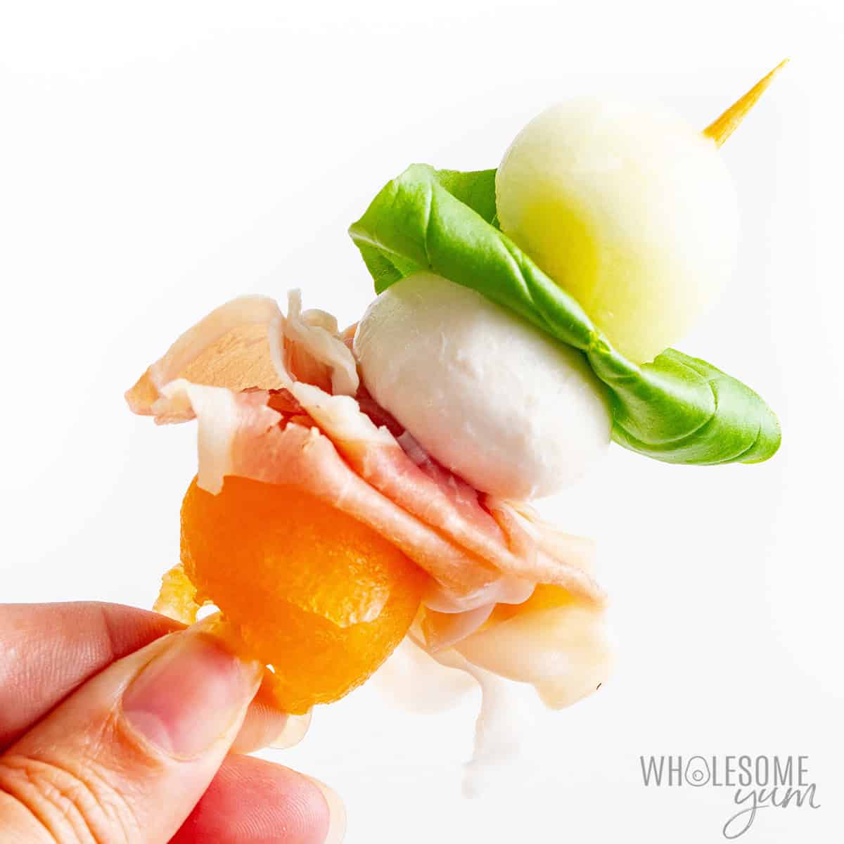 Skewers assembled with cantaloupe, honeydew melon, prosciutto, fresh mozzarella, and basil leaves.