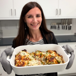 Maya holding a dish of spinach artichoke chicken.