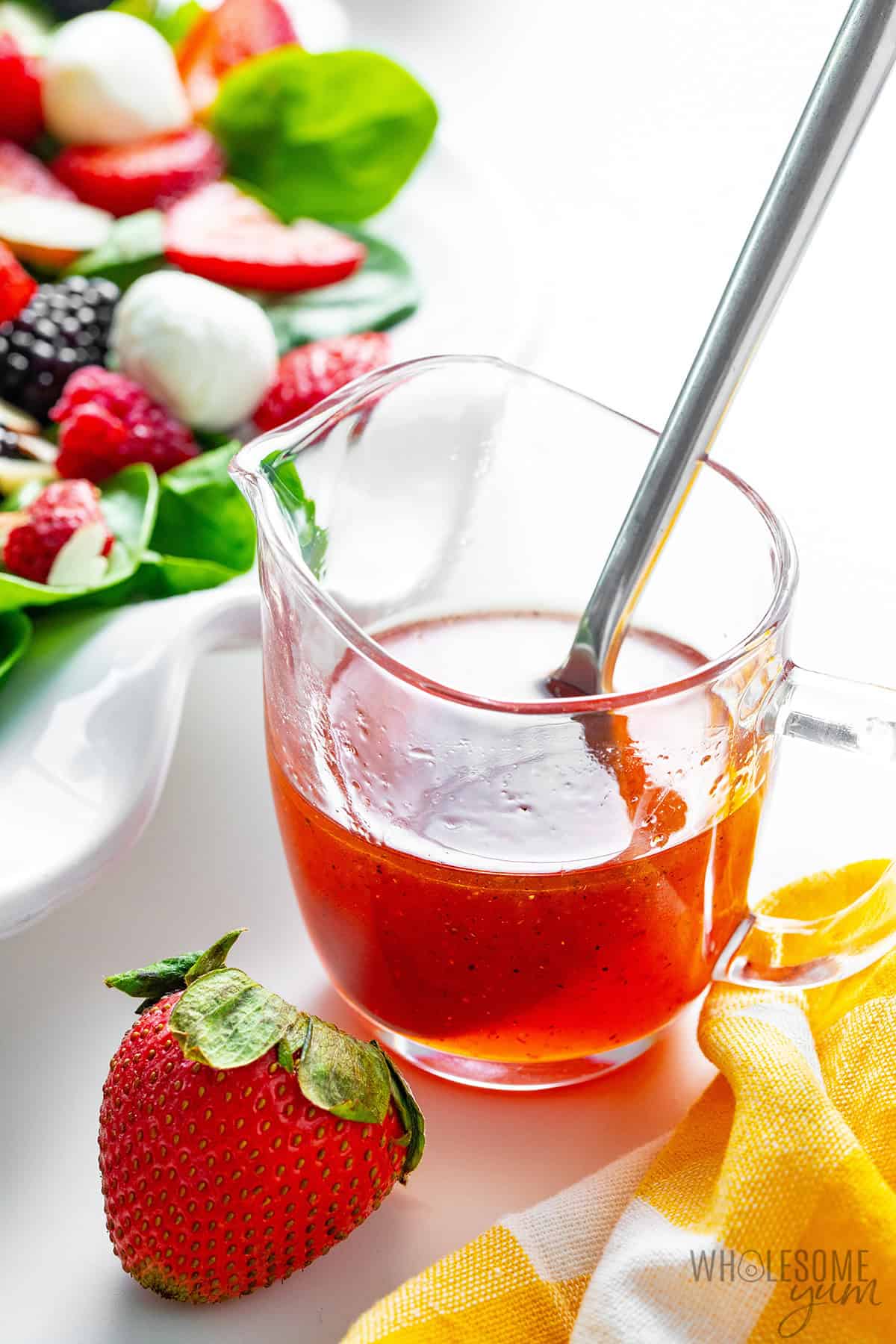 Strawberry vinaigrette dressing beside a fresh summer salad.