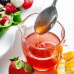 Strawberry vinaigrette in a measuring cup with a spoon drizzling the dressing.