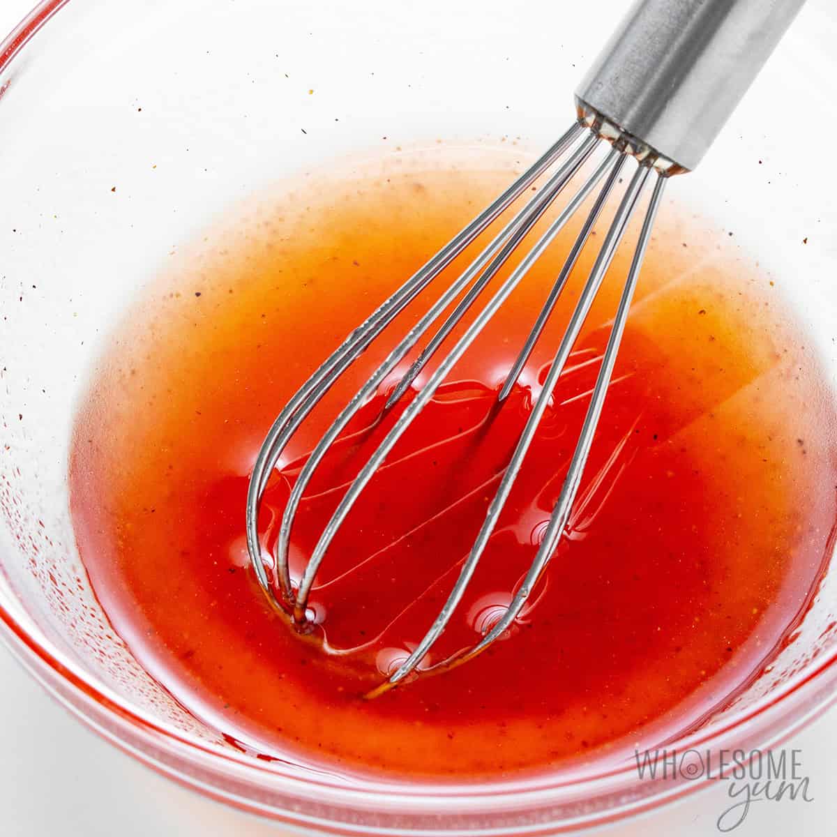 Strawberry dressing in a small glass bowl with a whisk.