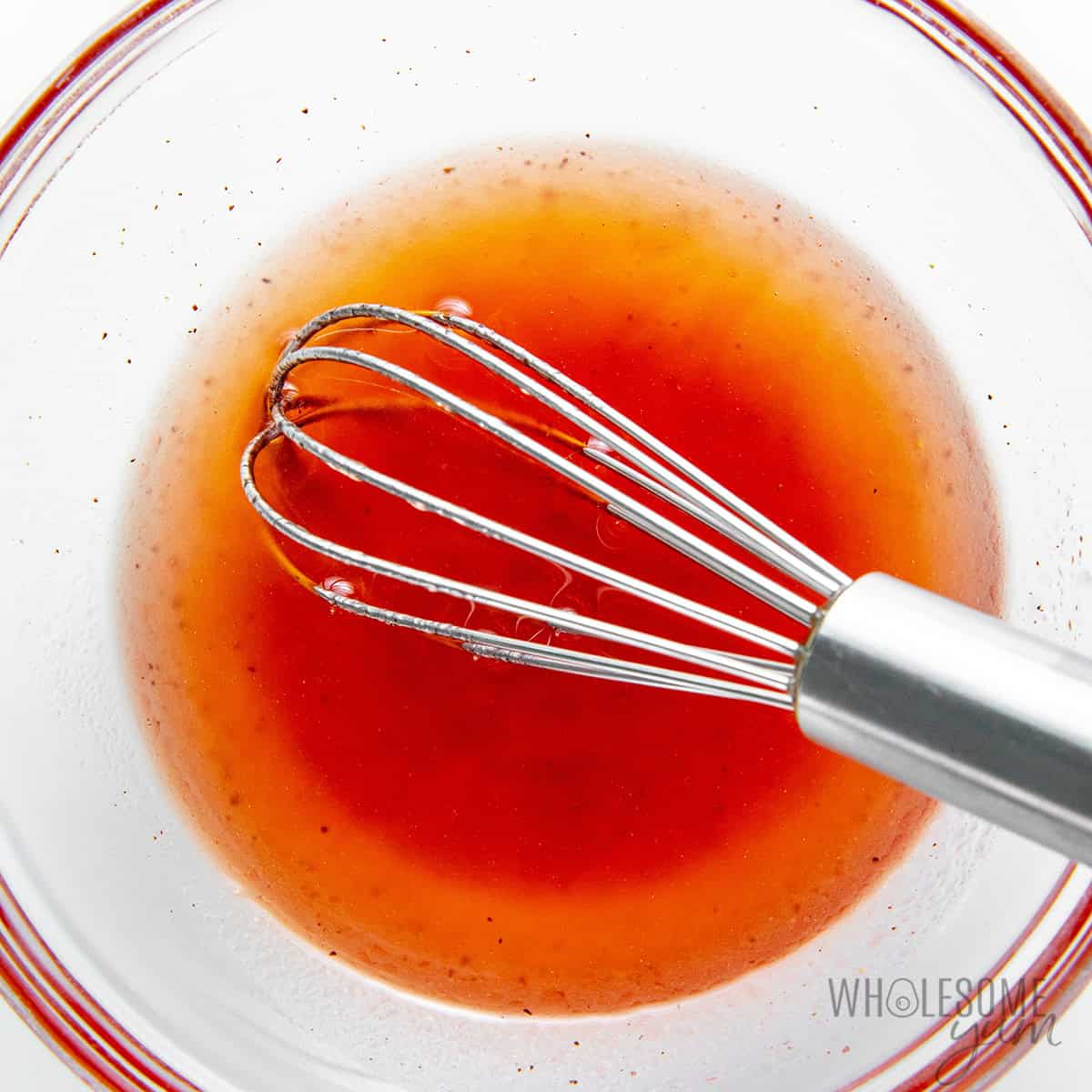 Whisking sugar free strawberry vinaigrette in a bowl.