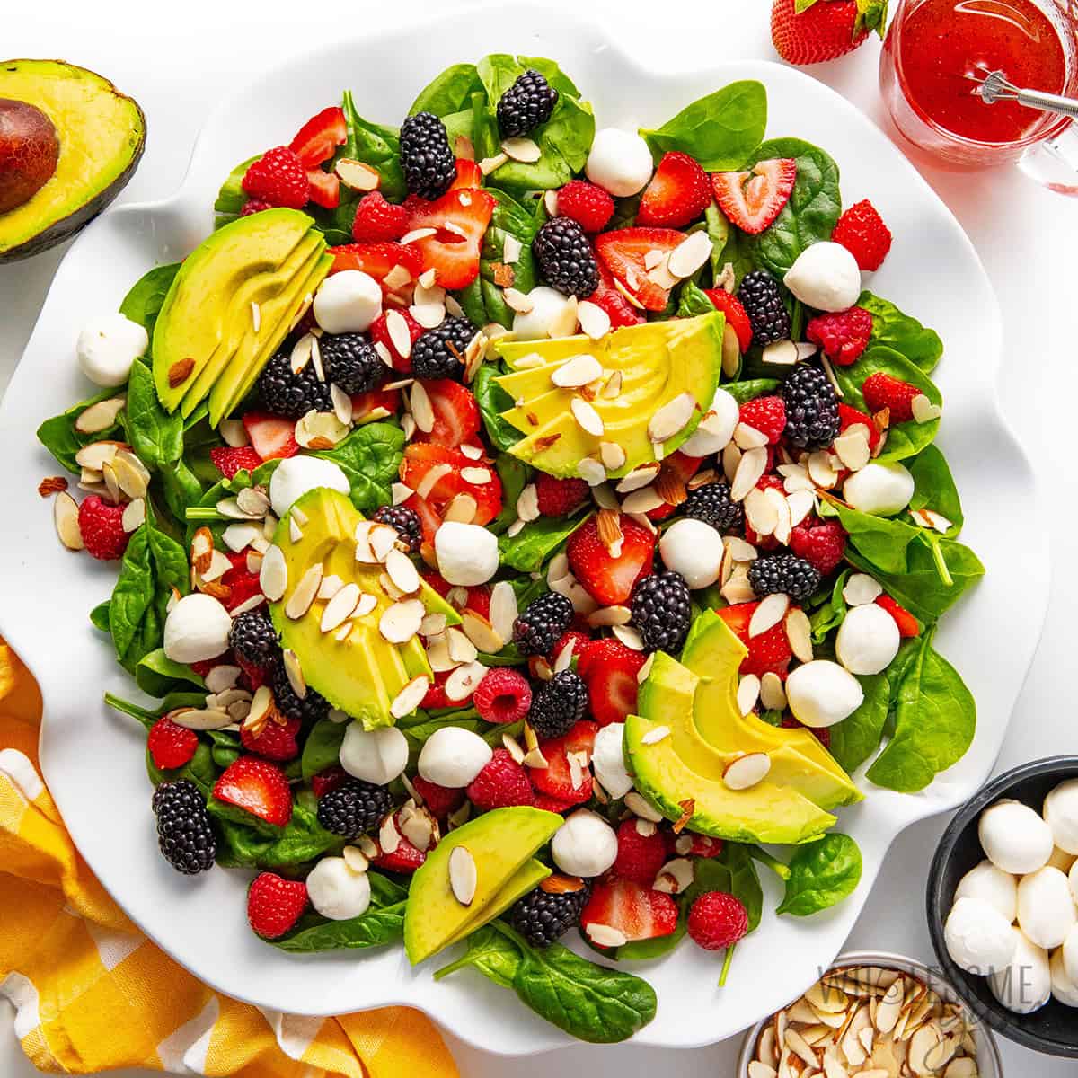 Summer salad recipe finished with avocado, almonds, and dressing.
