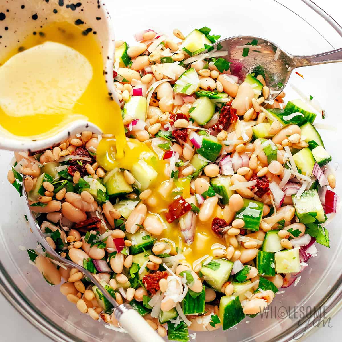 Pouring dressing over the cannellini bean salad recipe.