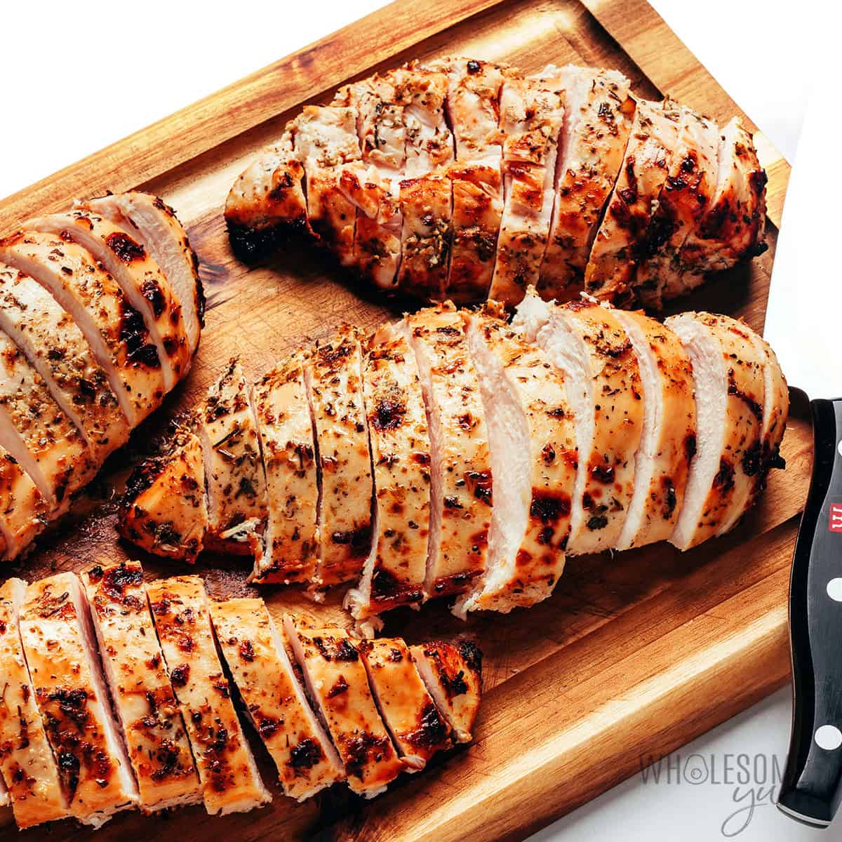 Juicy chicken sliced against the grain on a cutting board.