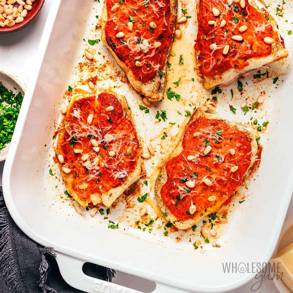 Baked grouper recipe topped with pine nuts, parmesan cheese, and parsley.