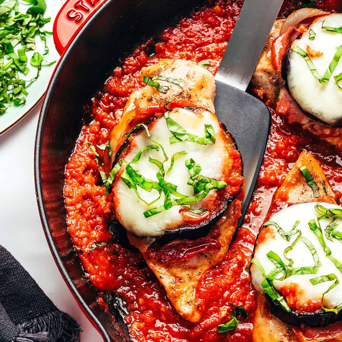 Chicken Sorrentino on a spatula in a skillet.