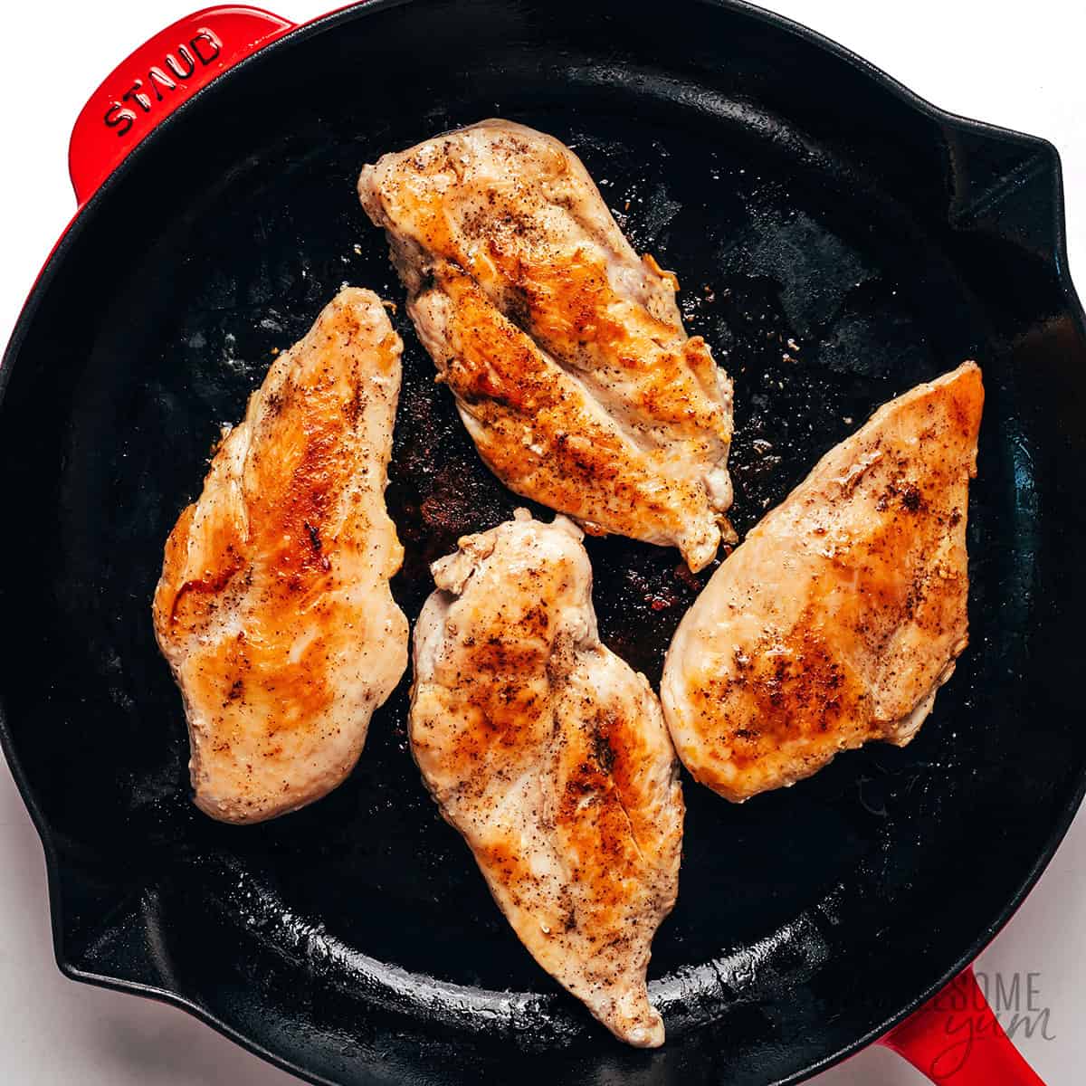 Chicken cutlets seared in a skillet.