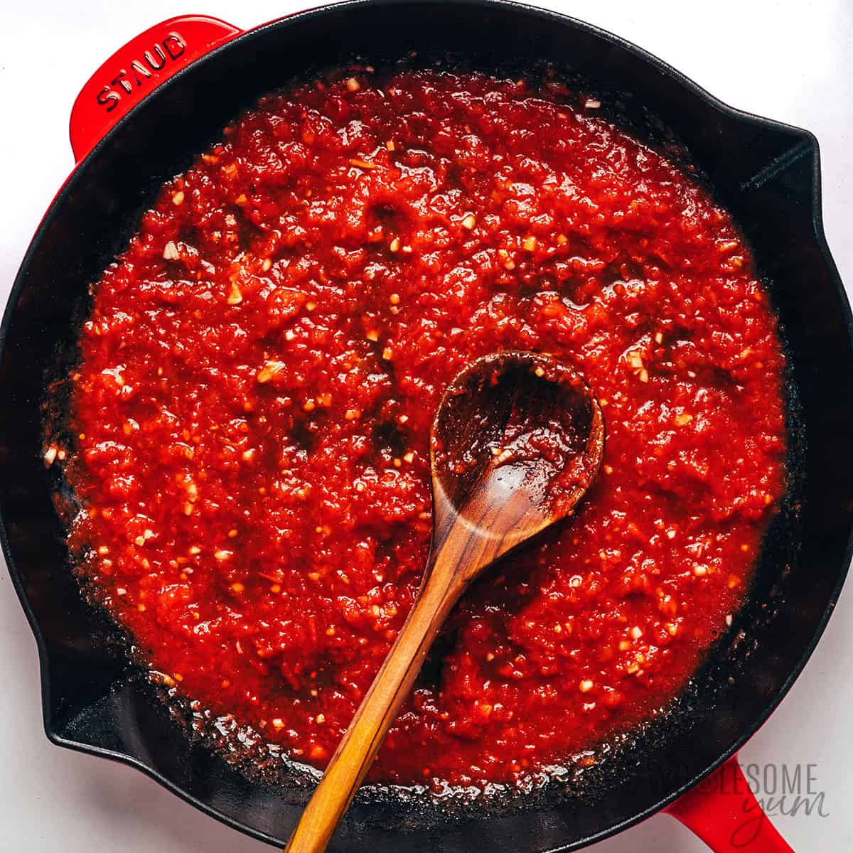 Marinara sauce in a skillet with a wooden spoon.