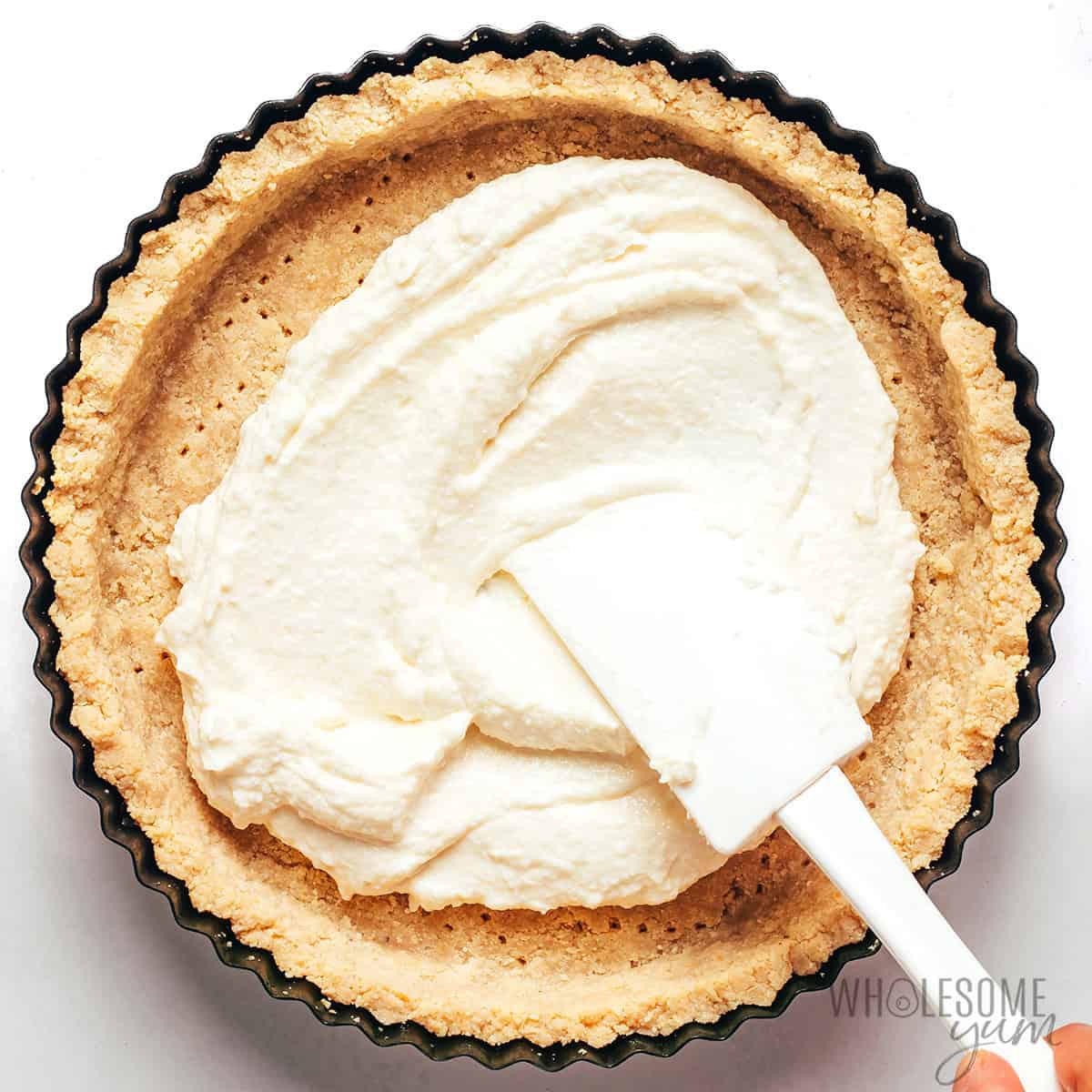 Spreading creamy feta filling into the baked tart crust.