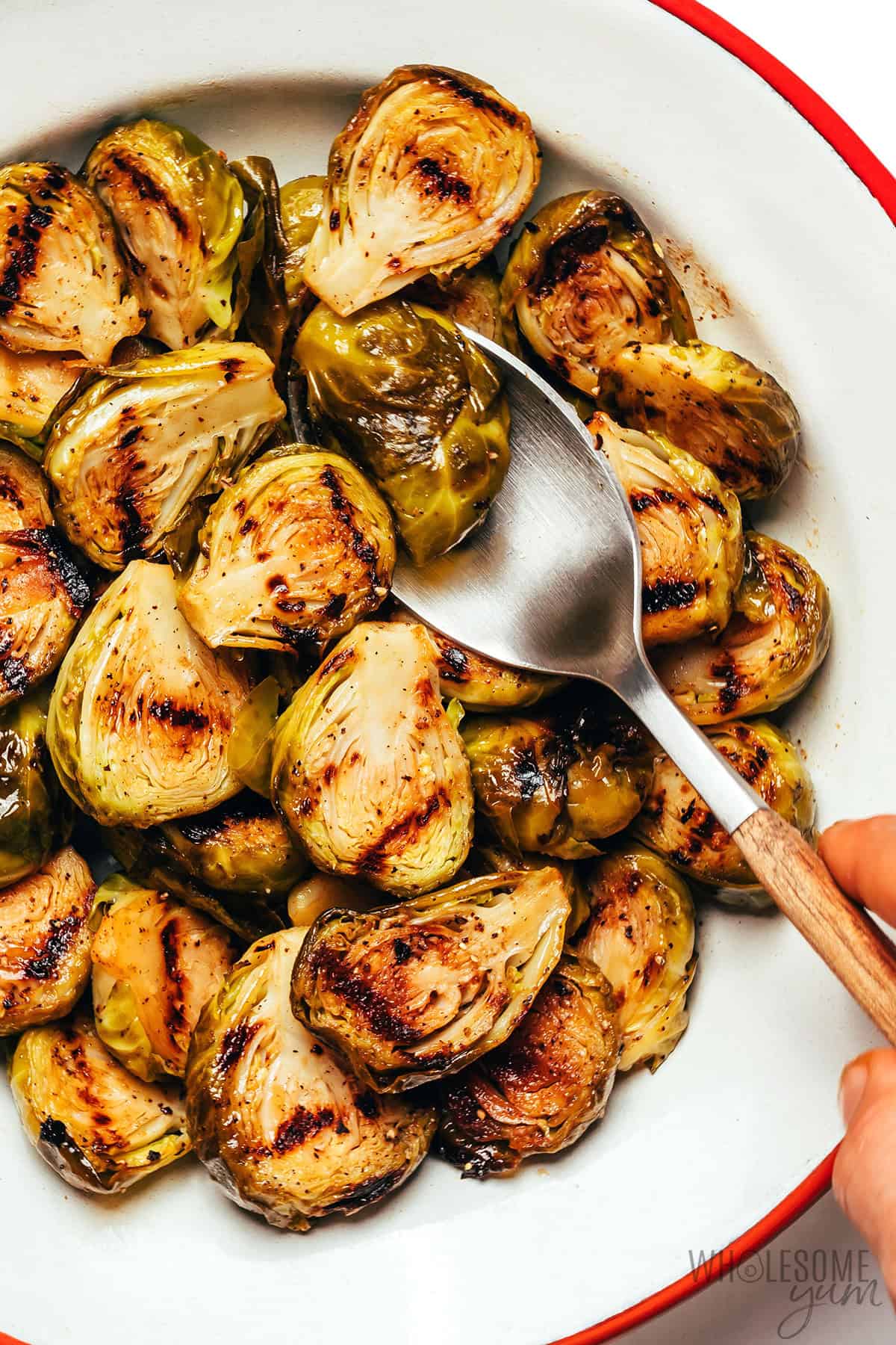 Grilled Brussels sprouts served in a bowl with a spoon.