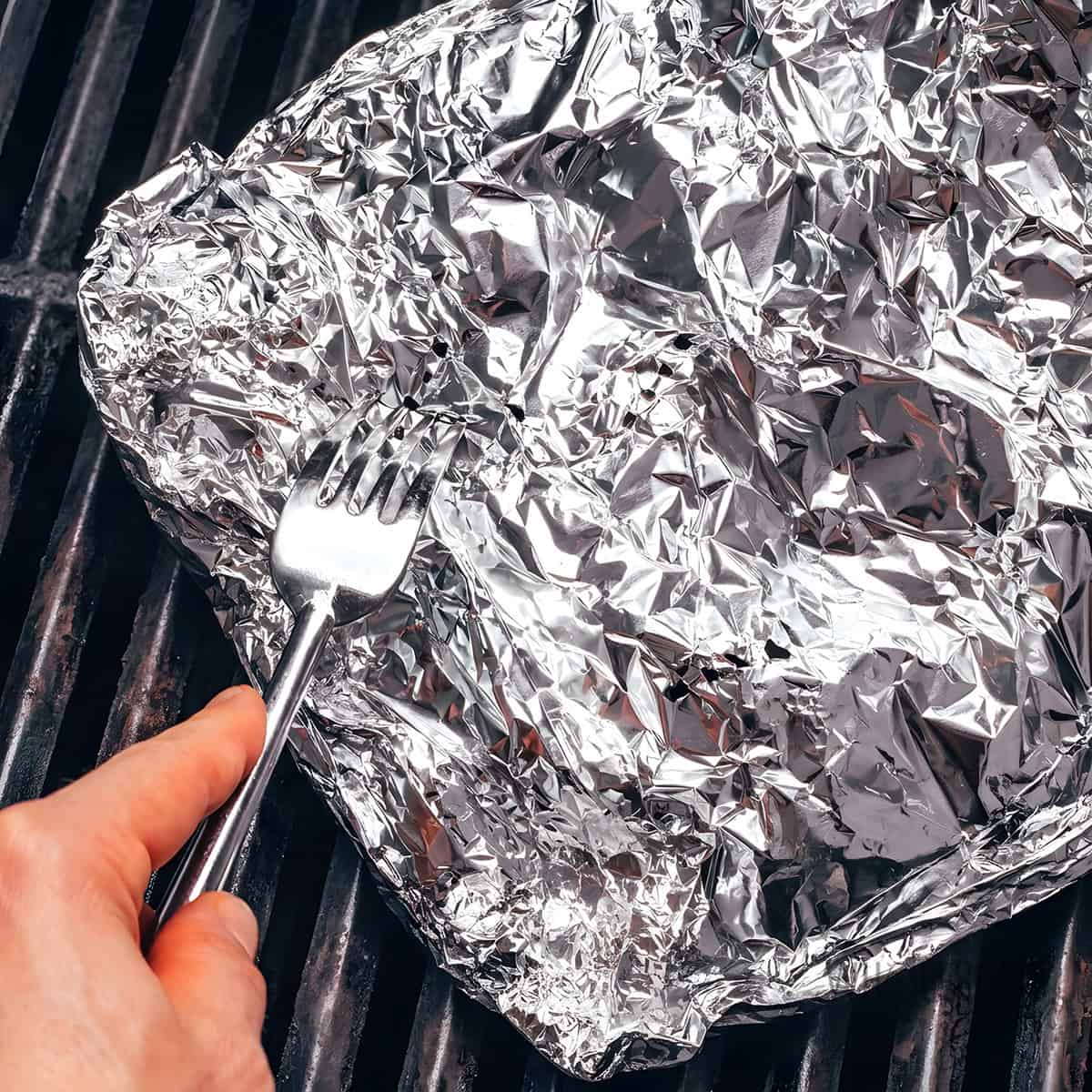 Sealed foil packet of Brussels sprouts on the grill.