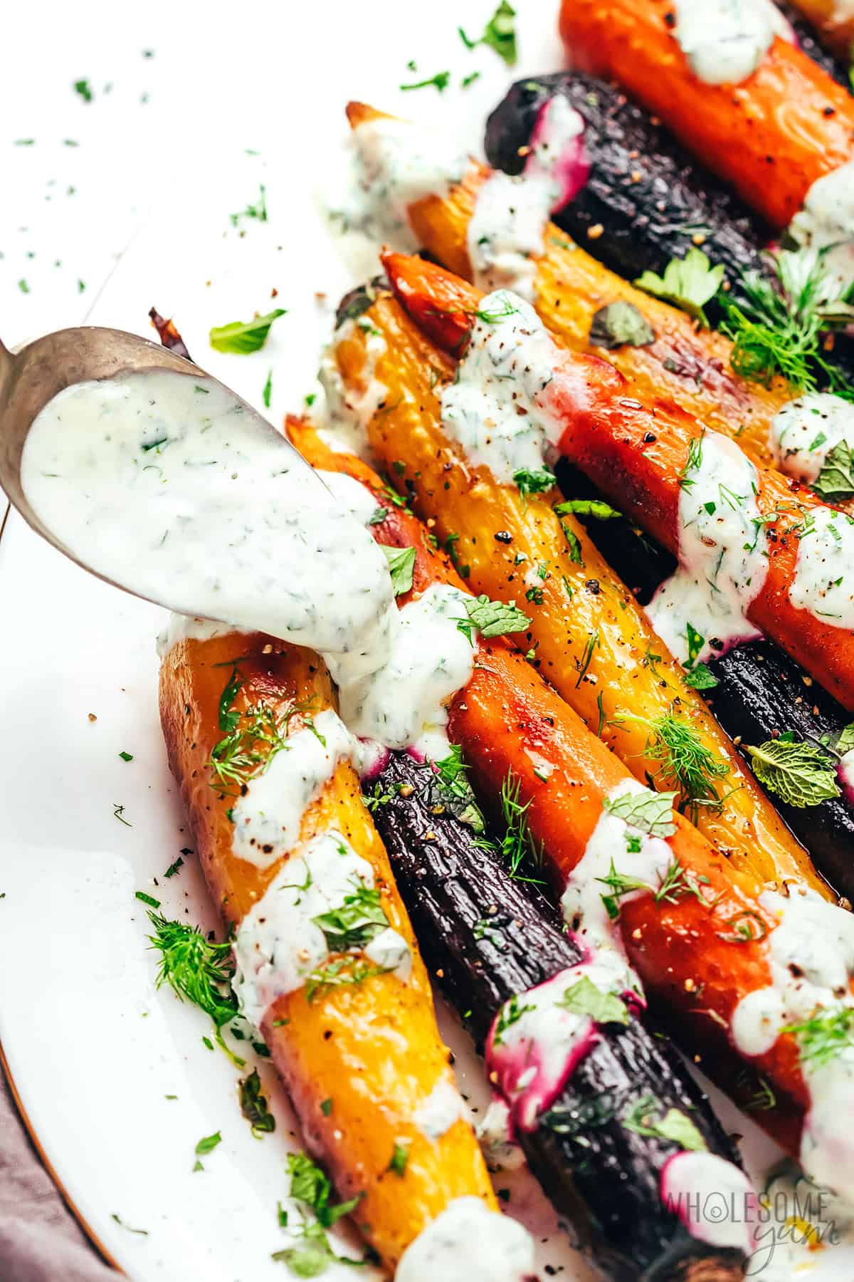 Flavorful roasted rainbow carrots topped with yogurt sauce and fresh herbs.