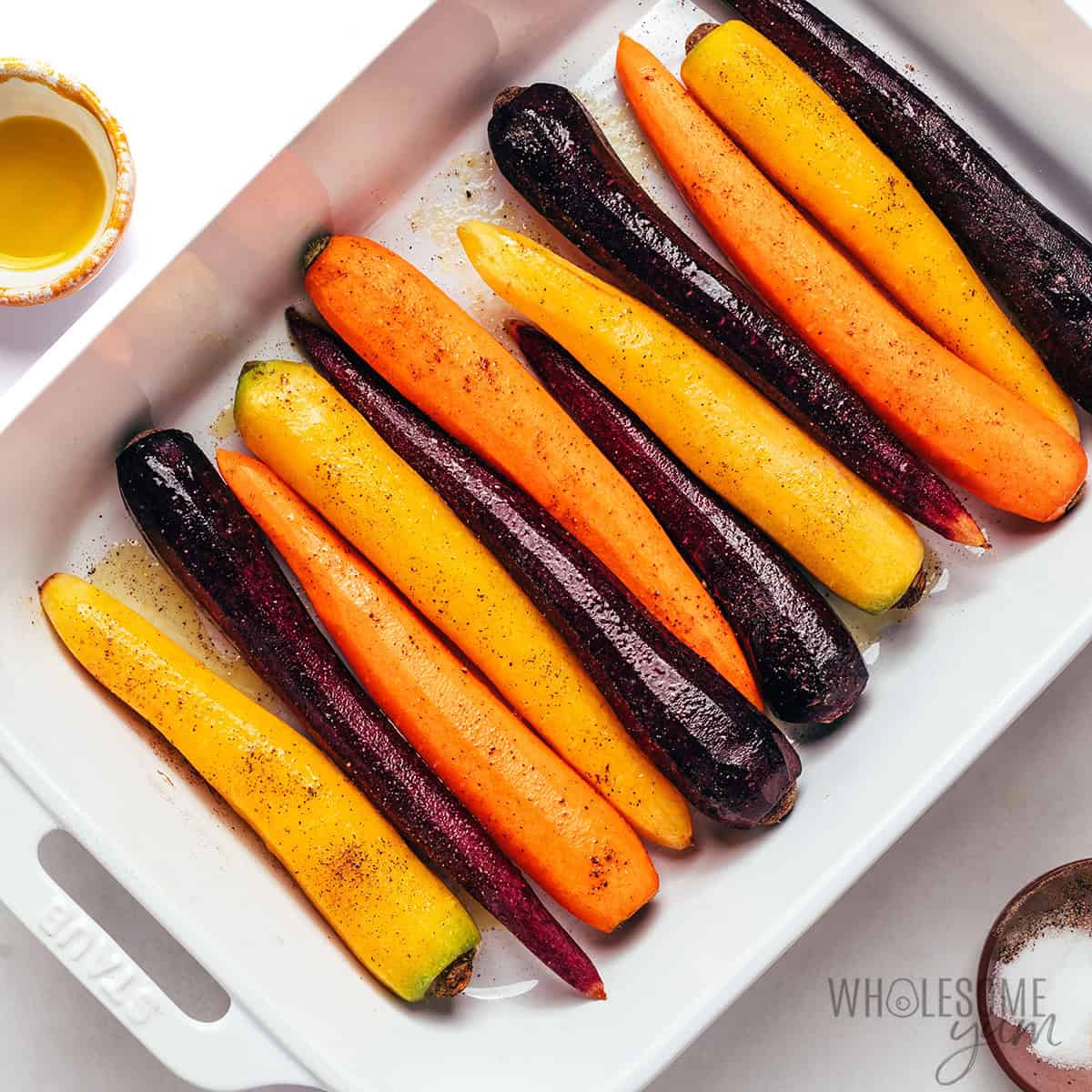 Seasoned rainbow carrots in a baking dish.