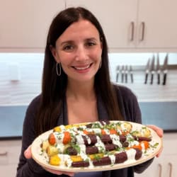 Maya holding a platter of rainbow carrots.