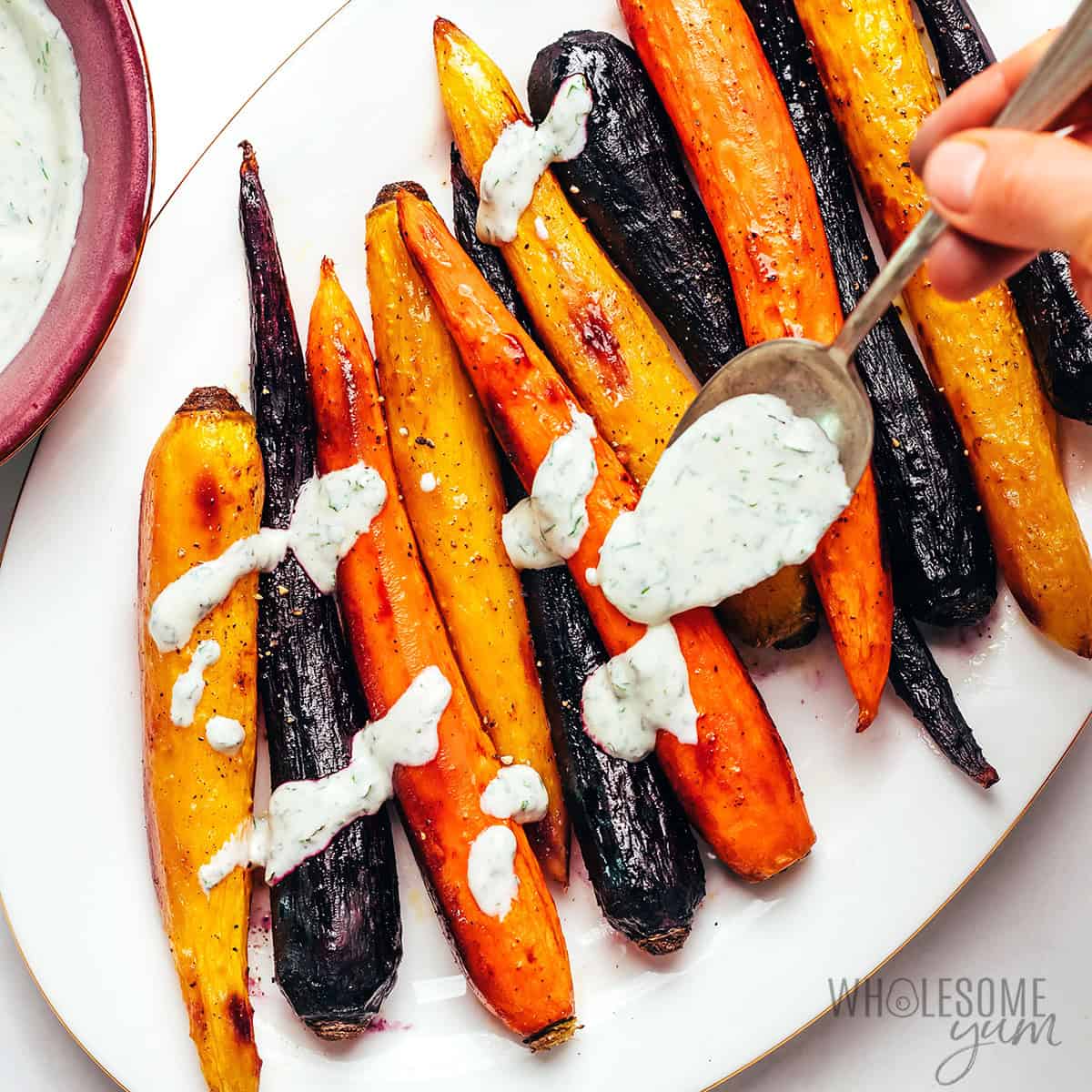 Yogurt herb sauce drizzled over roasted rainbow carrots.