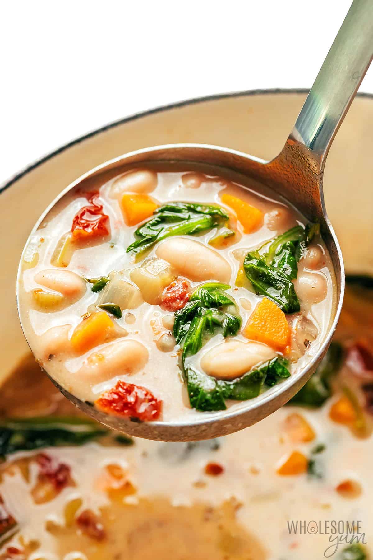 Creamy white bean soup in a ladle.