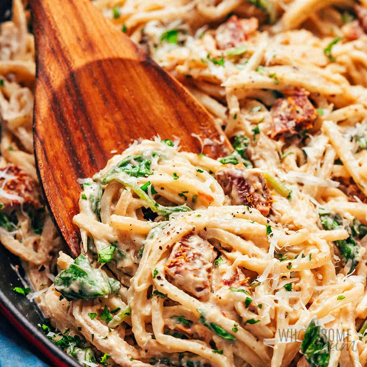 Creamy hearts of palm pasta in a skillet with a wooden spoon.