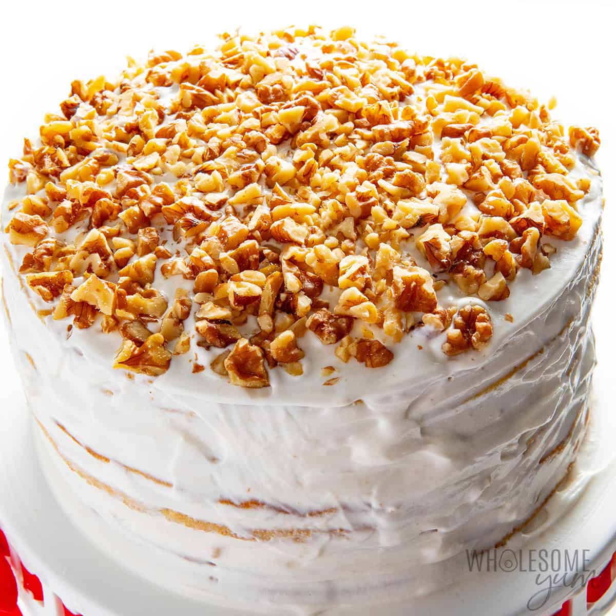 Fully assembled honey cake topped with chopped walnuts, served on a cake stand.