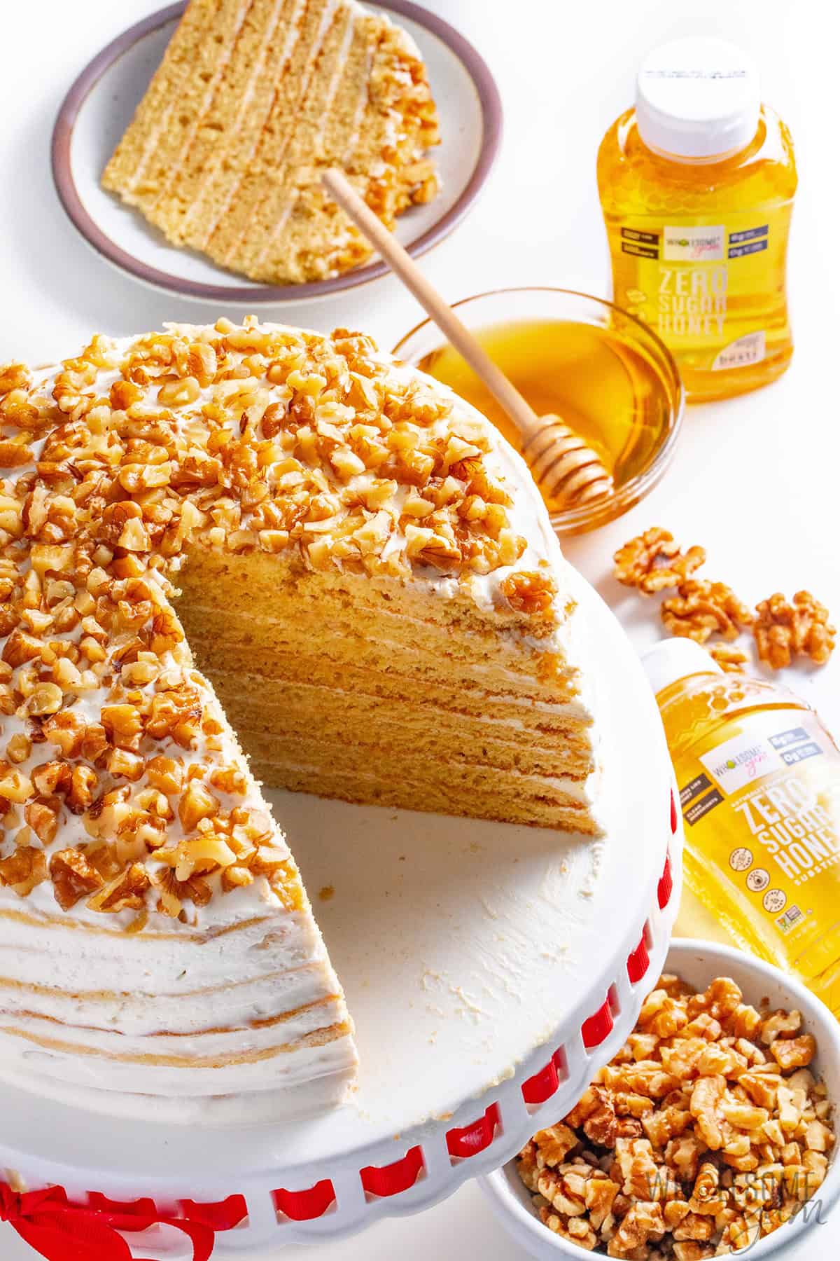 Russian honey cake with layers of soft, tender cake and creamy frosting, topped with crunchy chopped walnuts and surrounded by honey.