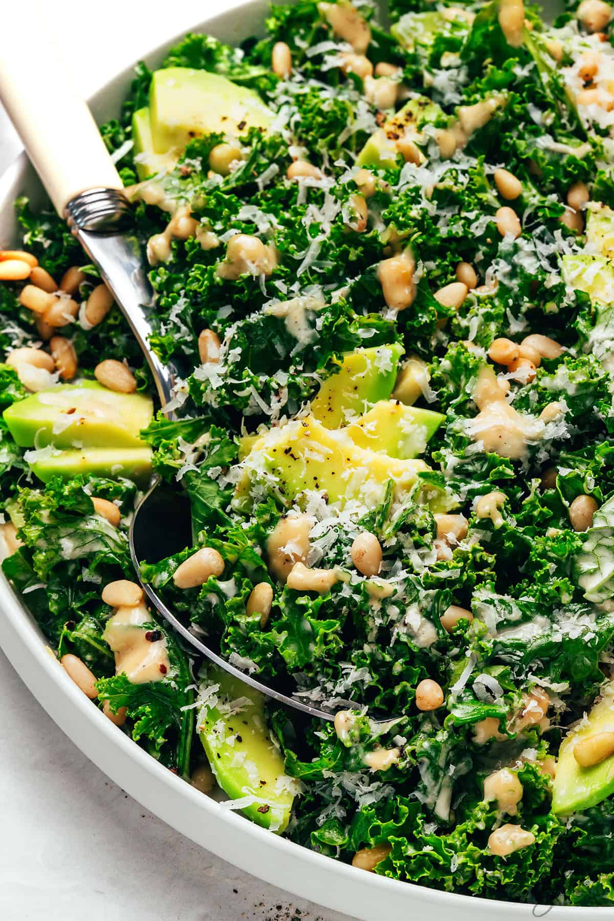 Creamy, tender kale Caesar salad topped with pine nuts and Parmesan cheese.