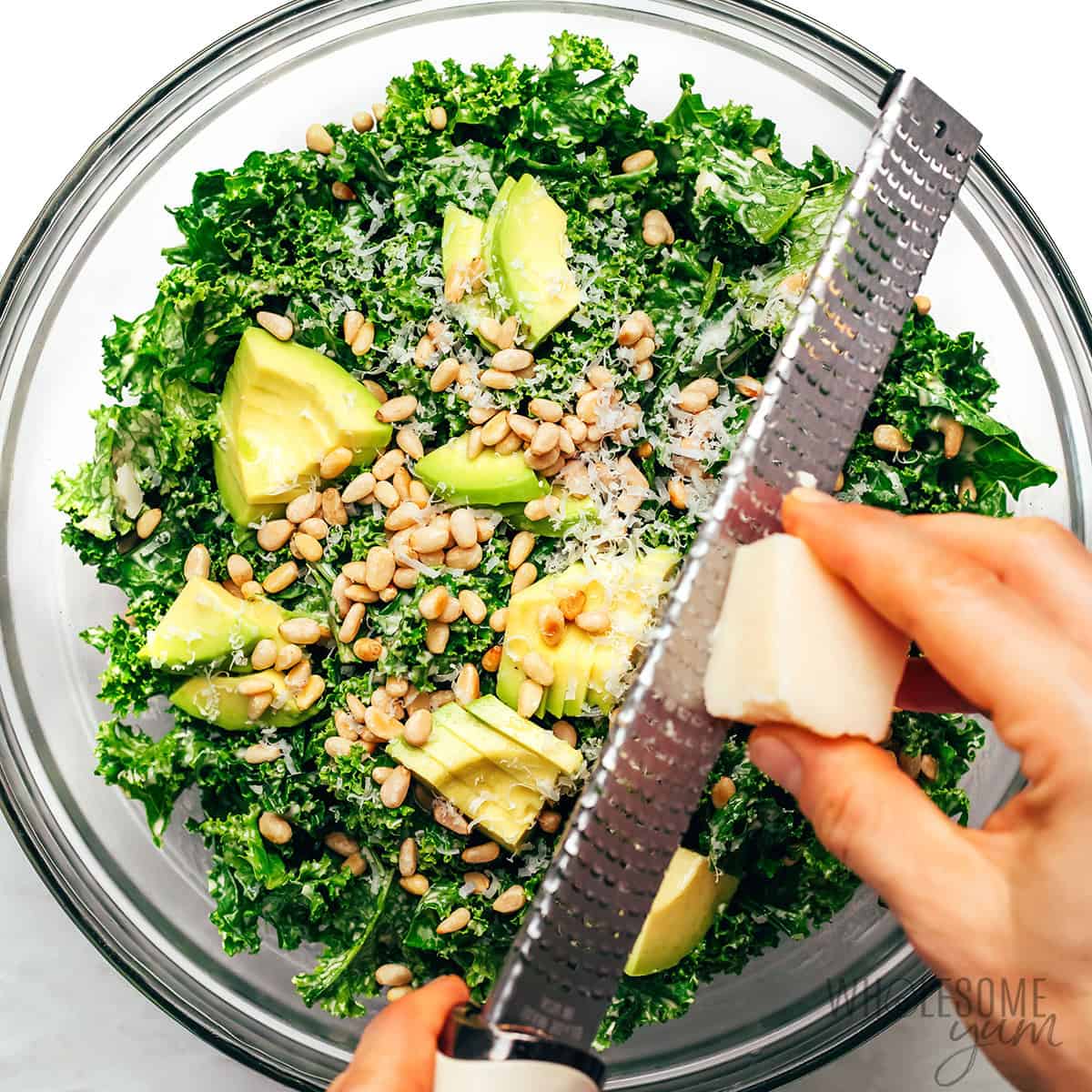 Salad topped with avocado, pine nuts, and Parmesan cheese.