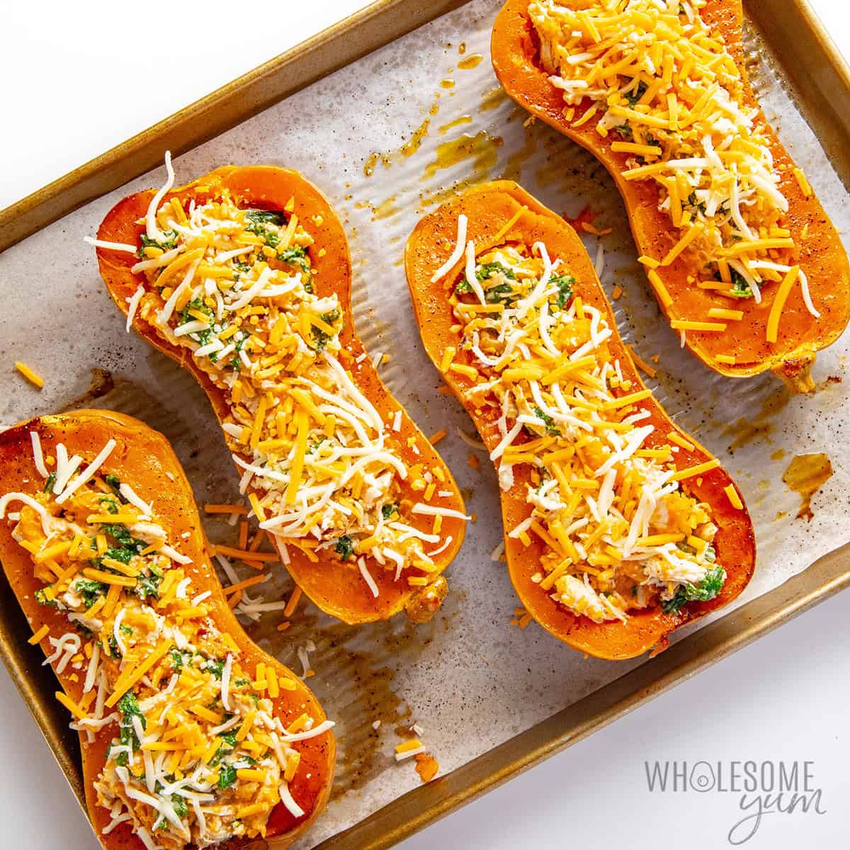 Filling and cheese added to butternut squash halves.