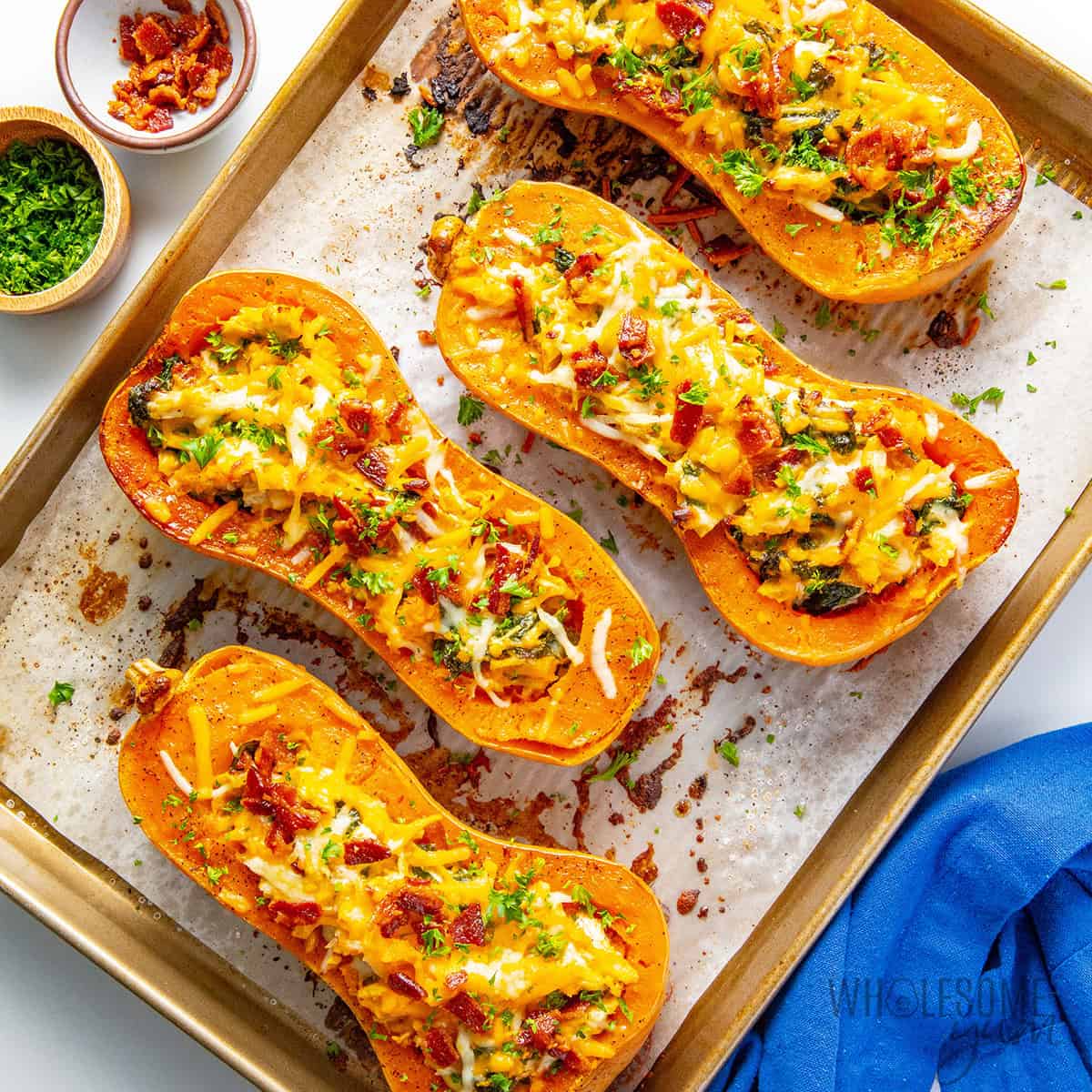 Stuffed butternut squash on a sheet pan garnished with fresh parsley.