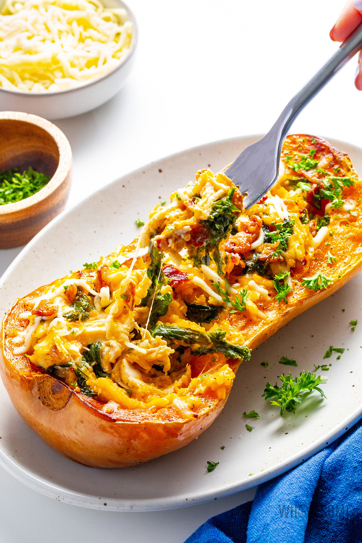 Creamy, sweet and savory stuffed butternut squash with cheese pull using a fork.